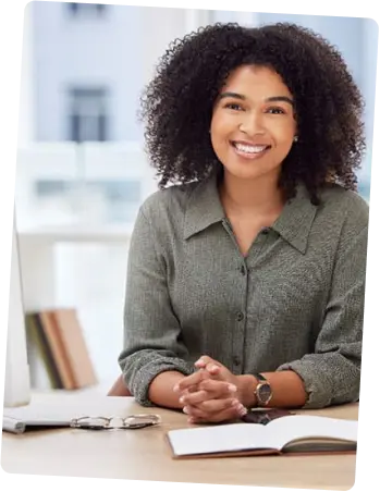 Smiling woman sitting at a desk with an open book.